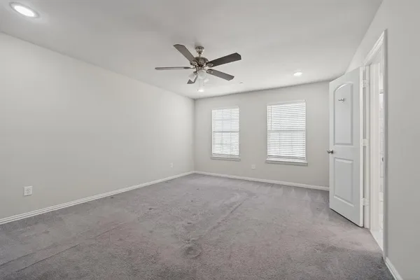an empty room with windows and fan