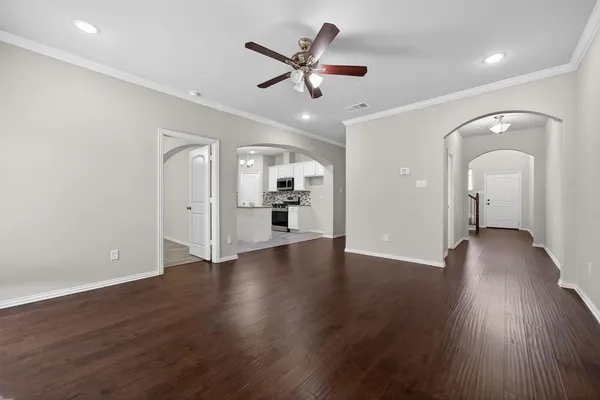 an empty room with wooden floor and a ceiling fan