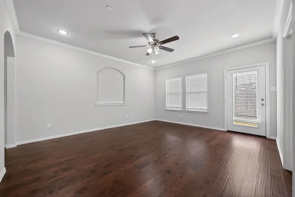 an empty room with wooden floor ceiling fan and windows