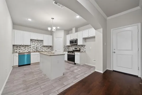 a kitchen with granite countertop white cabinets and stainless steel appliances