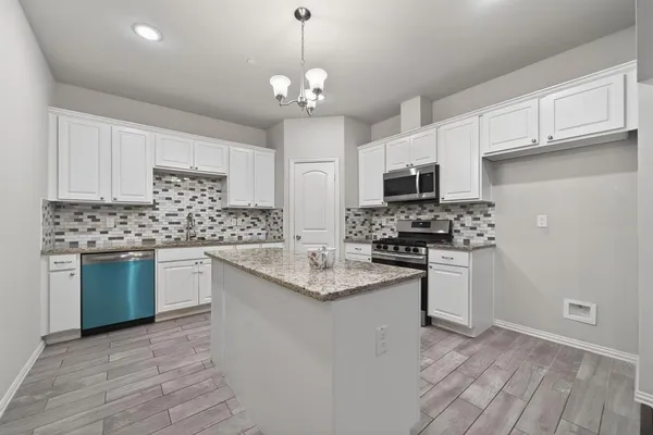 a kitchen with kitchen island granite countertop stainless steel appliances a stove sink and microwave