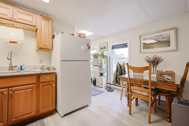 a white kitchen with a refrigerator a table and chairs