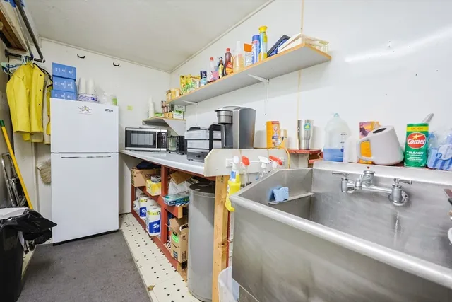 a utility room with stainless steel appliances a refrigerator and a sink
