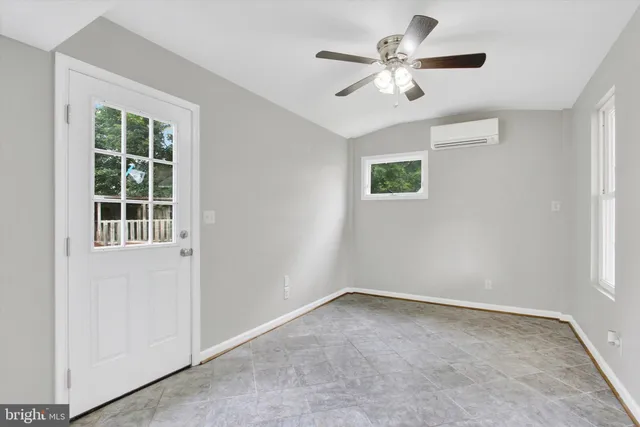 an empty room with windows and fan