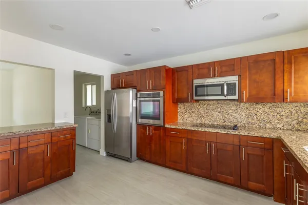a large kitchen with granite countertop a sink and wooden cabinets