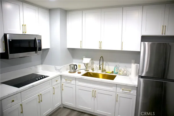 a kitchen with a sink a microwave a refrigerator and cabinets