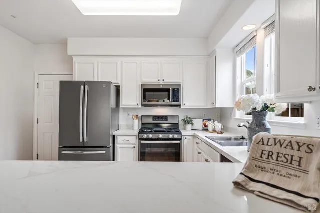 a kitchen with white cabinets and stainless steel appliances