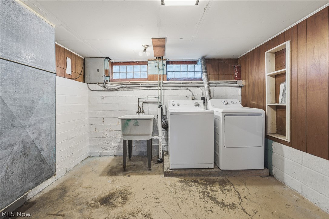 311 Fowles Road Berea, OH 44017 - Photo 30 of 40 Utility room featuring a laundry sink, wood paneling, built-in shelving, glass block windows, and concrete flooring