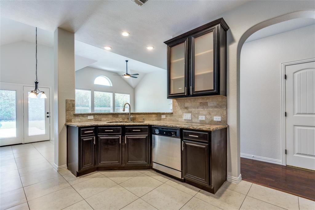2344 Ranchview Drive Little Elm, TX 75068 - Photo 8 of 24 Kitchen featuring dark wood cabinetry, a stainless steel dishwasher, and a stone-finish backsplash