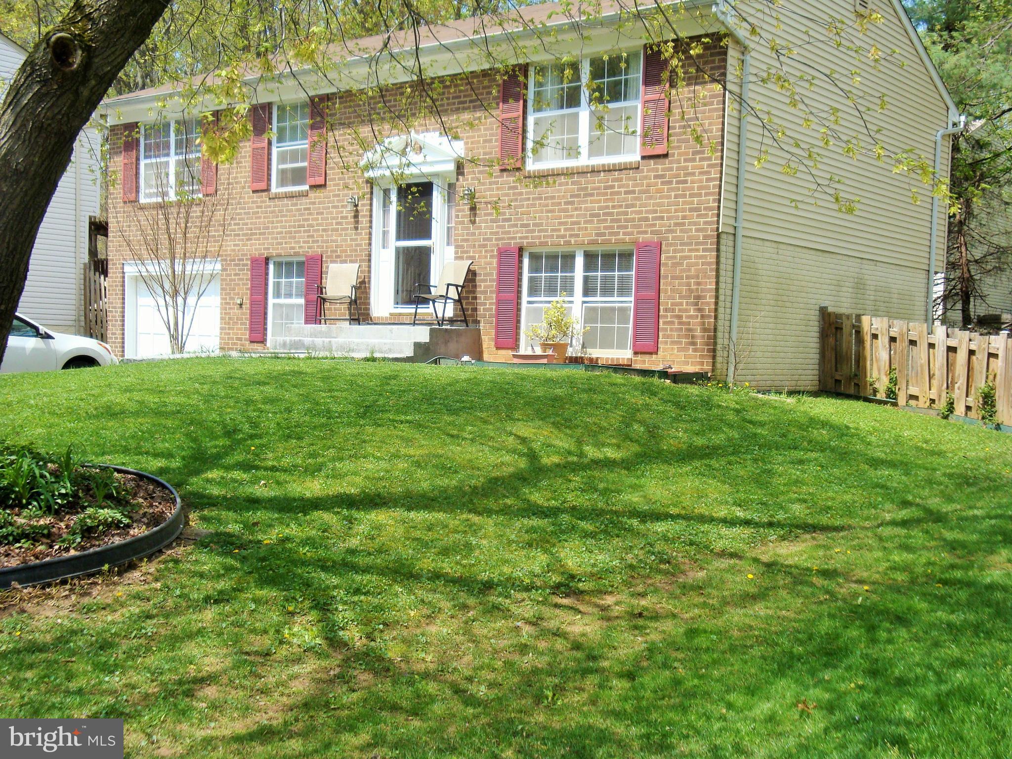 10159 Marshall Pond Road Burke, VA 22015 - Photo 2 of 28 a view of a brick house with a yard and table and chairs under an umbrella