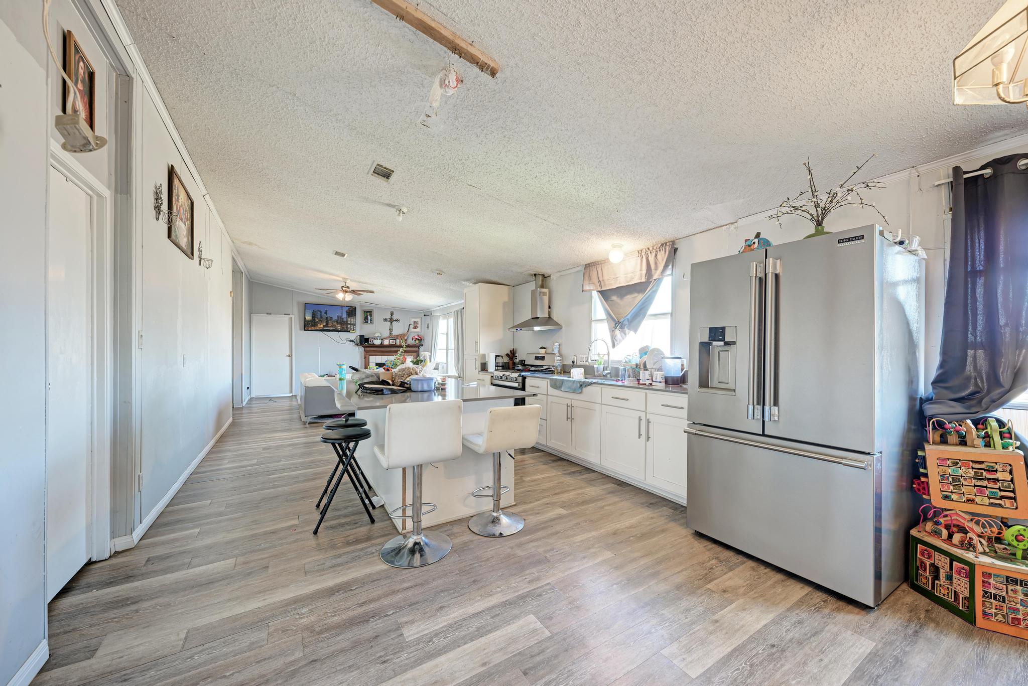 20113 Maynard Court Coupland, TX 78615 - Photo 11 of 37 a kitchen with a refrigerator a sink dishwasher a stove and white cabinets with wooden floor