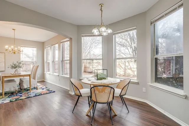 a dining room with wooden floor a chandelier a wooden table and chairs