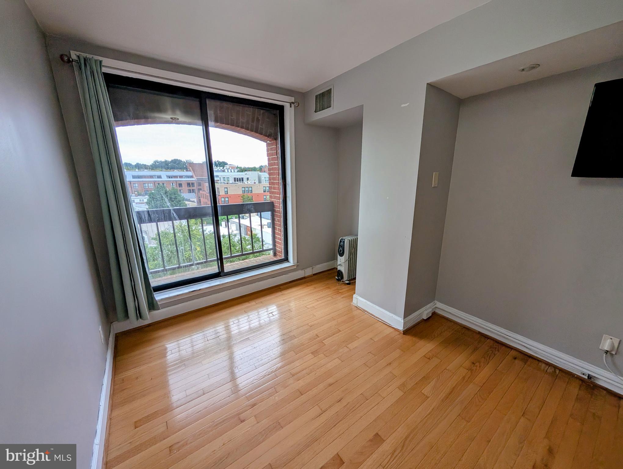 1080 Wisconsin Avenue Northwest, Unit 501 Washington, DC 20007 - Photo 20 of 36 a view of an empty room with wooden floor and a window