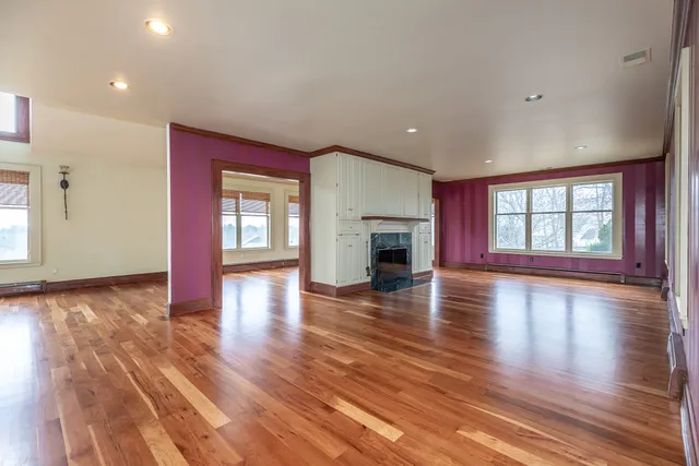 a view of empty room with fireplace and wooden floor