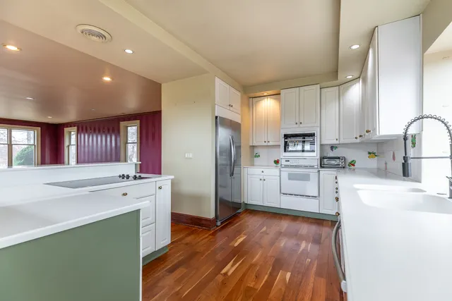 a kitchen with white cabinets appliances and wooden floor