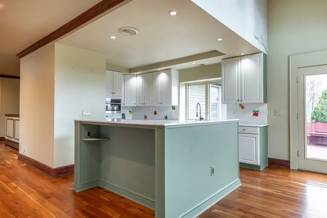 a view of a hallway to a room with wooden floor cabinet and windows