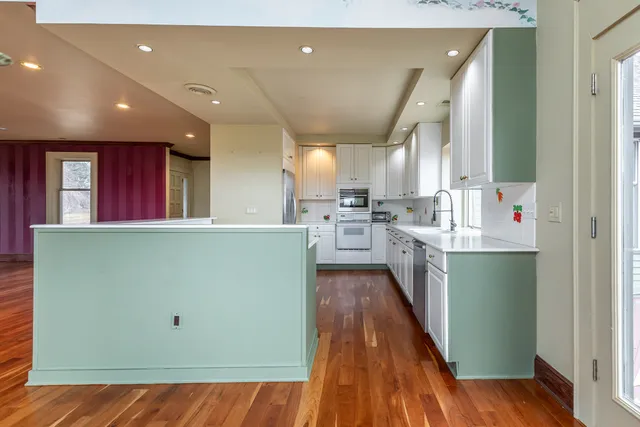 a view of a kitchen with kitchen island a sink wooden floor and a counter top space