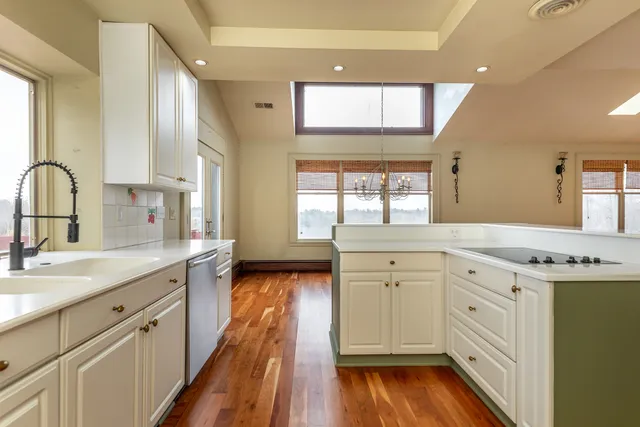 a view of a kitchen with a sink a window and wooden floor