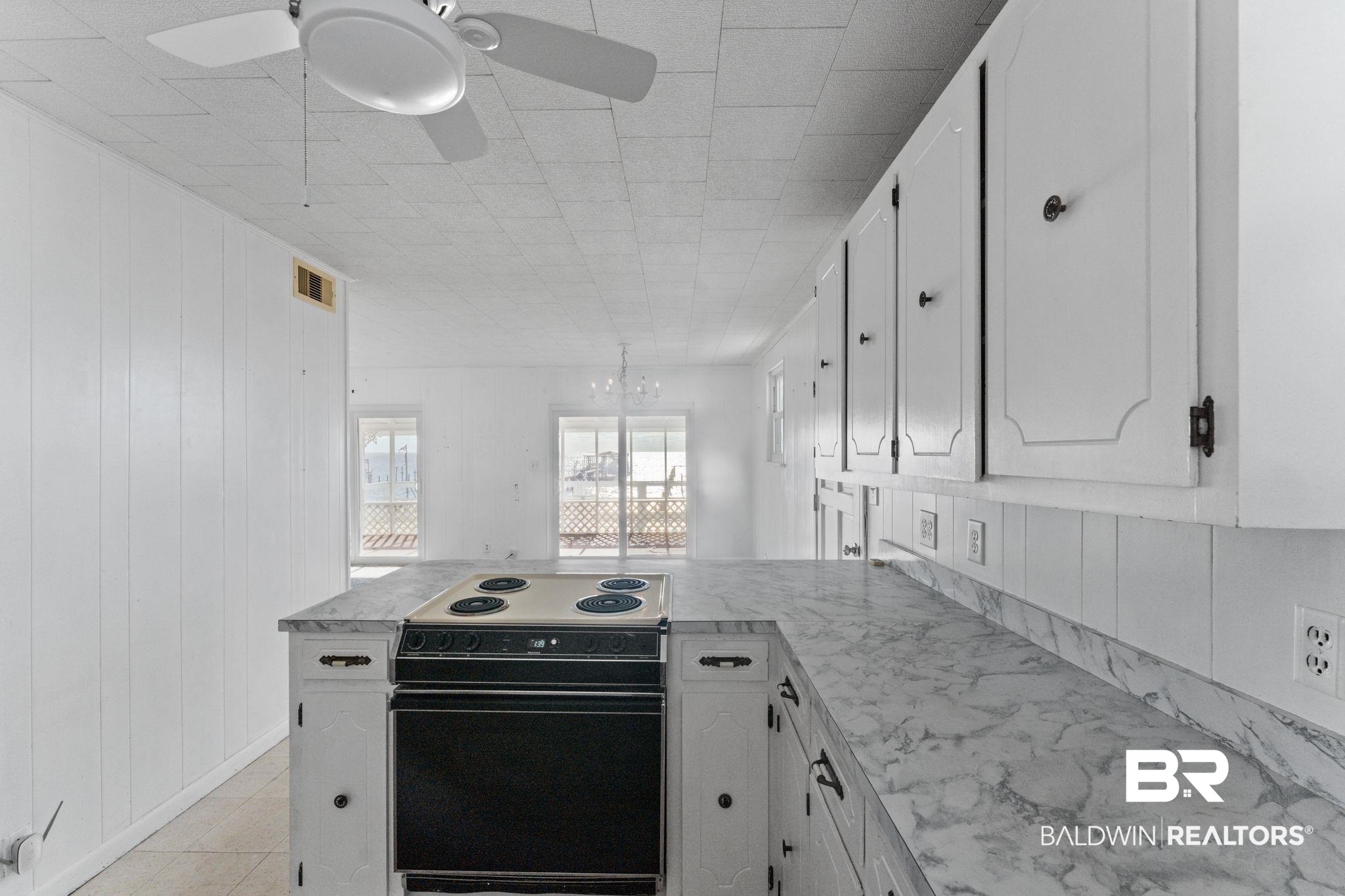 8959 Shore Drive Foley, AL 36535 - Photo 26 of 53 Kitchen with black electric range, white cabinetry, a peninsula, light countertops, and wooden walls