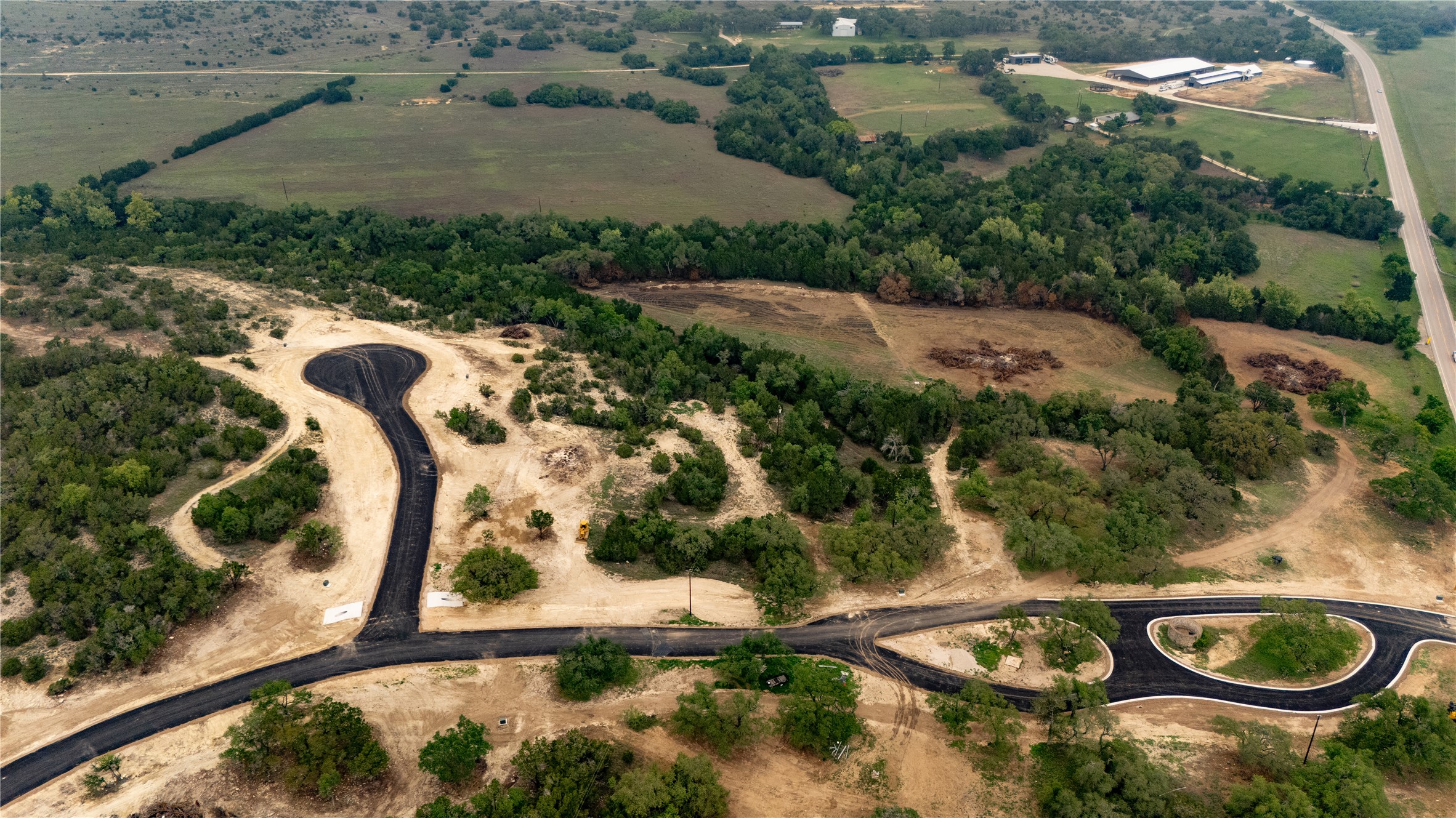 Lot 26 Ranch Road 165 Dripping Springs, TX 78620 - Photo 2 of 13 Aerial perspective showcasing a new residential development with newly paved roads and cul-de-sacs, surrounded by mature trees and natural landscape