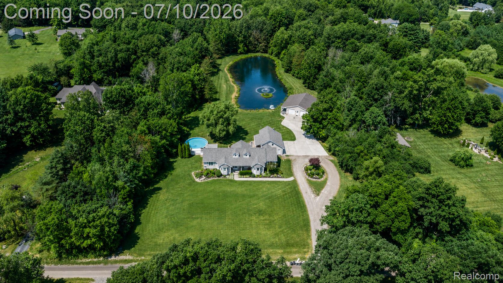2120 Montague Road Davison, MI 48423 - Photo 3 of 37 Expansive property featuring a residence with multiple dormers, an in-ground swimming pool, a private pond with a fountain, a detached garage, and mature tree coverage