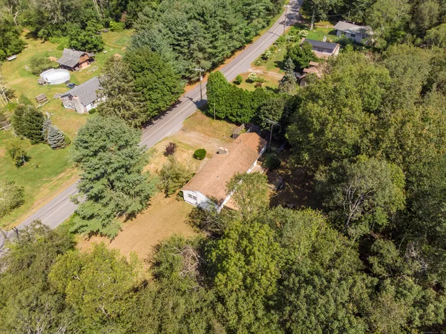 an aerial view of residential house with outdoor space and trees all around