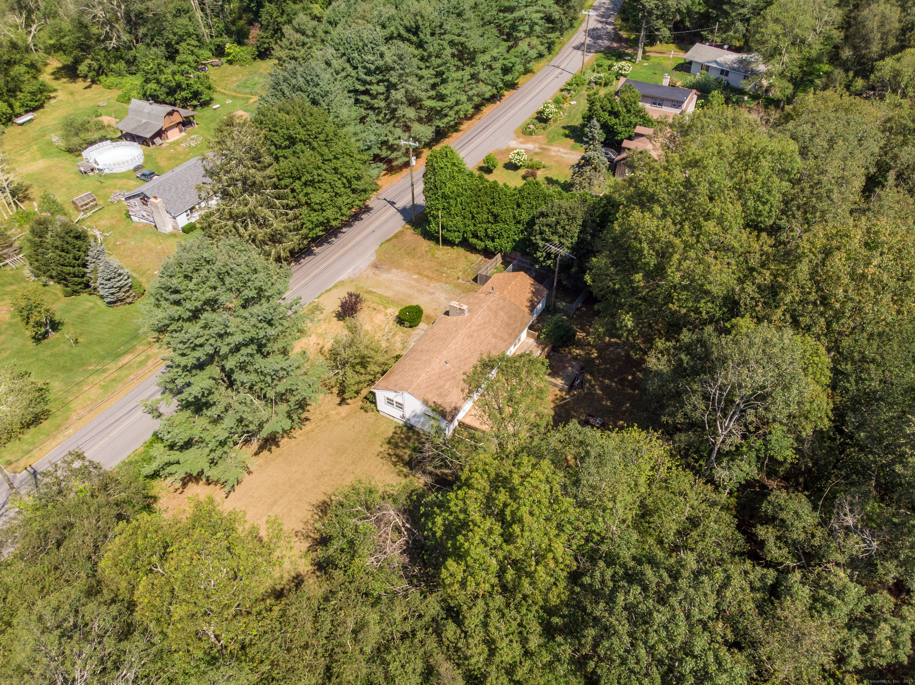 an aerial view of residential house with outdoor space and trees all around