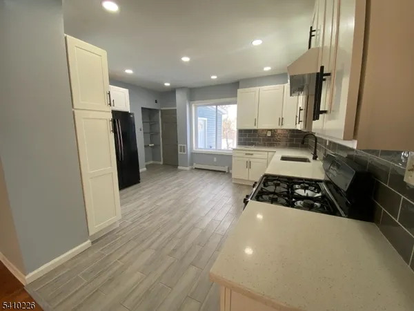 a kitchen with stainless steel appliances a refrigerator a sink a stove a microwave and wooden floor