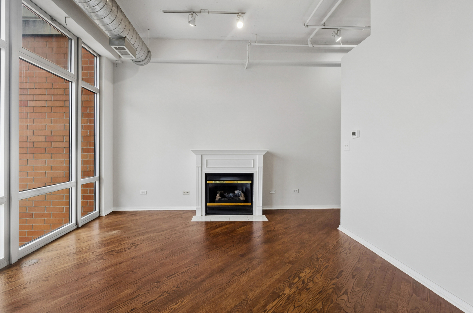950 West Monroe Street, Unit 809 Chicago, IL 60607 - Photo 11 of 21 an empty room with wooden floor a fireplace and windows
