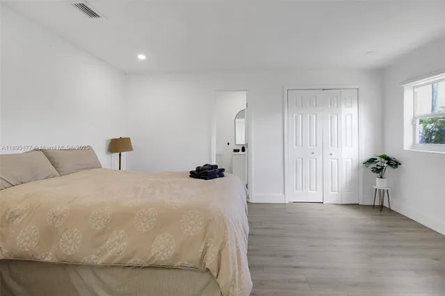 a spacious bedroom with a bed and wooden floor