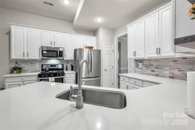 a kitchen with granite countertop a refrigerator a stove a sink a counter space and cabinets