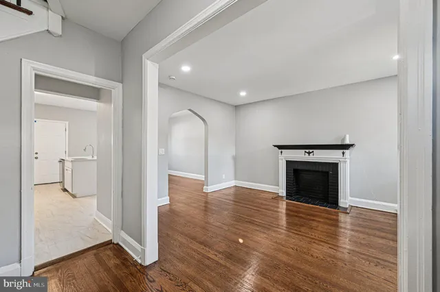 a view of a livingroom with wooden floor and a kitchen