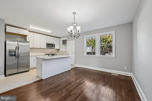 a large kitchen with stainless steel appliances granite countertop a refrigerator and a wooden floors