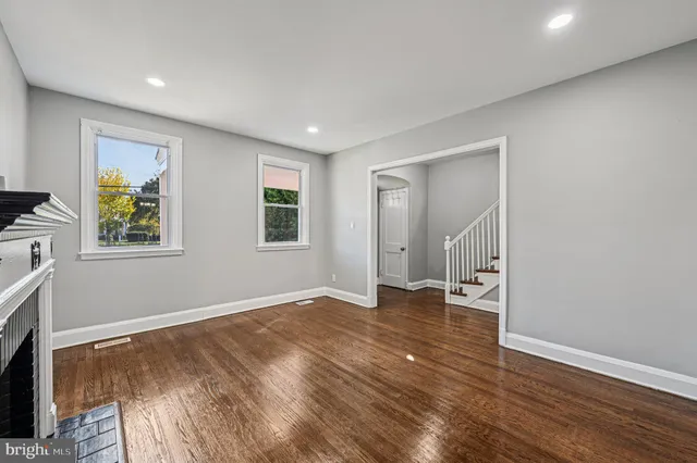 a view of an empty room with window and wooden floor
