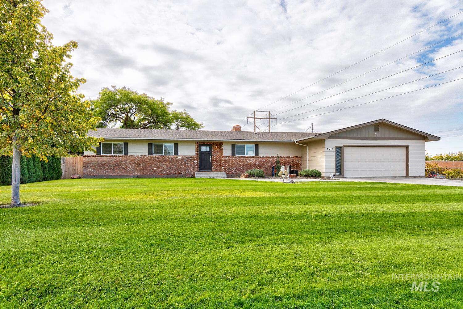 Ranch-style house featuring brick siding, a chimney, a garage, and concrete driveway