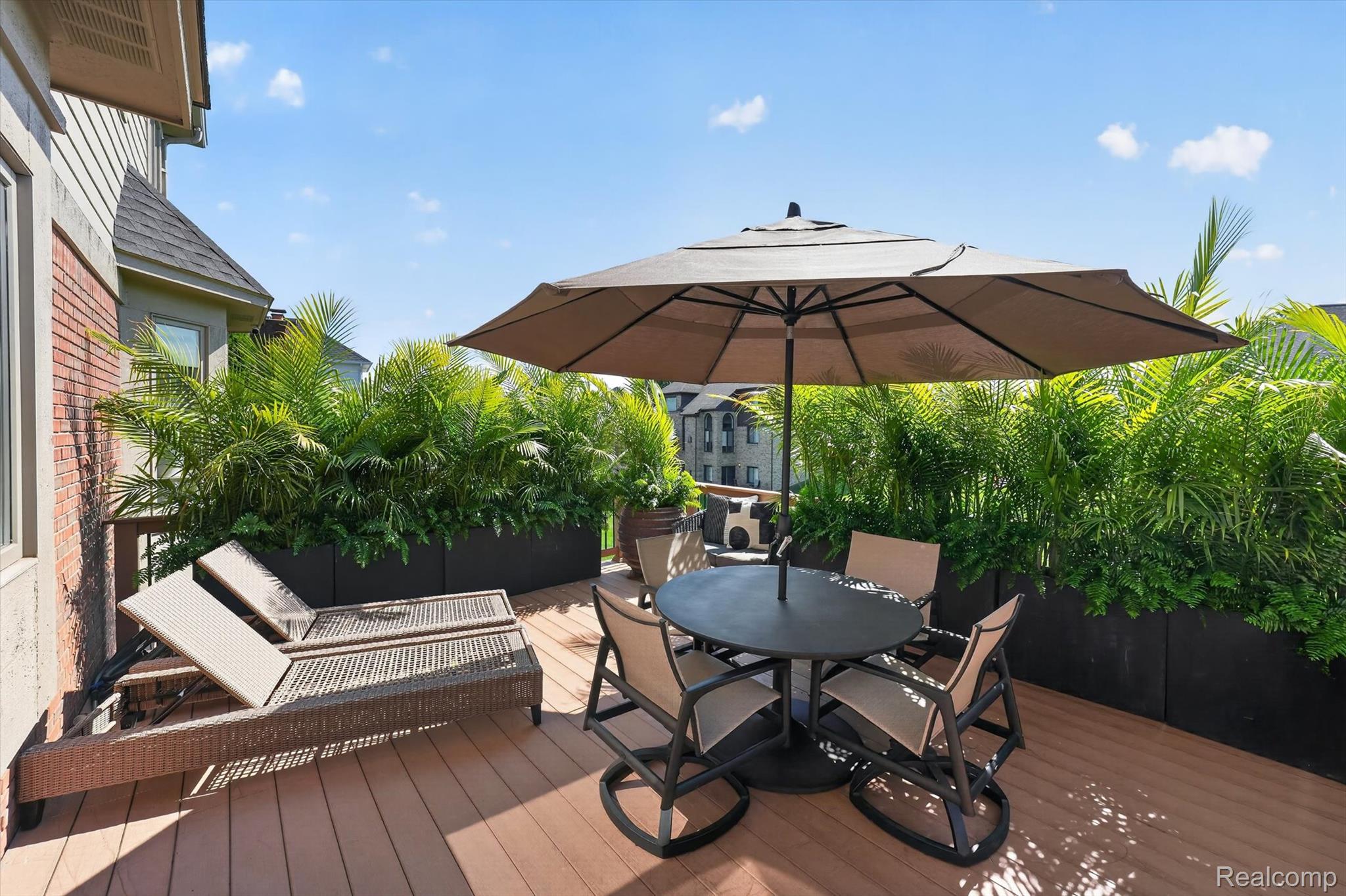 3804 Elk Drive Rochester, MI 48306 - Photo 54 of 75 Spacious outdoor deck featuring wood-finish flooring, built-in planters with lush greenery, and a neutral-toned privacy wall
