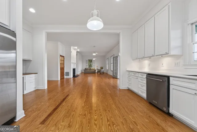 a view of an empty room with wooden floor and a ceiling fan