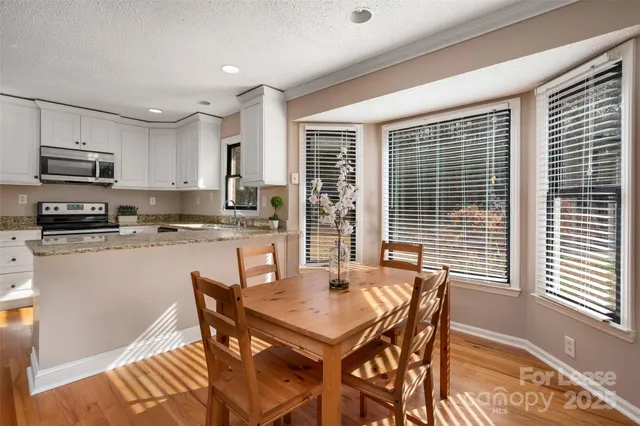 a kitchen with stainless steel appliances granite countertop a stove a refrigerator a kitchen island a table and chairs