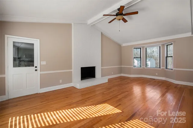 a view of a livingroom with a chandelier fan and wooden floor