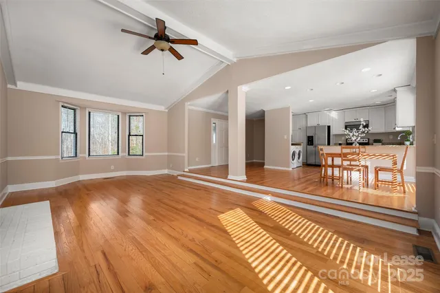 a view of an empty room with kitchen appliances and a ceiling fan