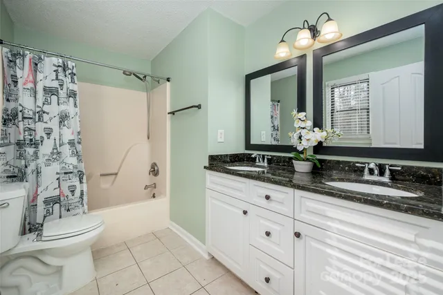 a bathroom with a granite countertop sink a toilet a mirror a vanity and shower