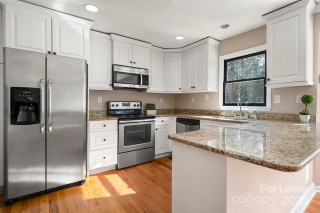 a kitchen with granite countertop a refrigerator a sink a stove a microwave and island