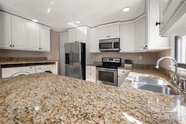 a kitchen with stainless steel appliances granite countertop a stove a sink a refrigerator a microwave and cabinets
