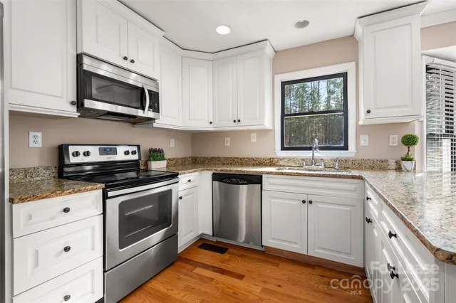 a kitchen with granite countertop white cabinets stainless steel appliances and a sink