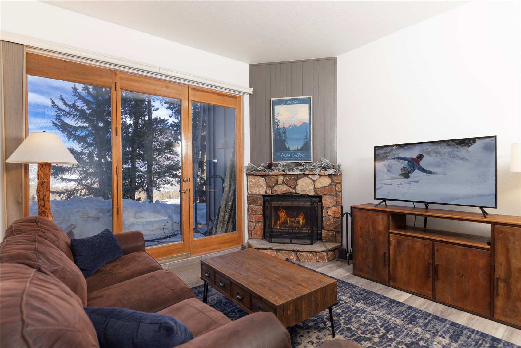 89410 Ryan Gulch Road, Unit 104 Silverthorne, CO 80498 - Photo 2 of 31 a living room with furniture a fireplace and a floor to ceiling window