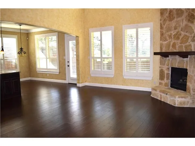 a view of an empty room with wooden floor and a fireplace