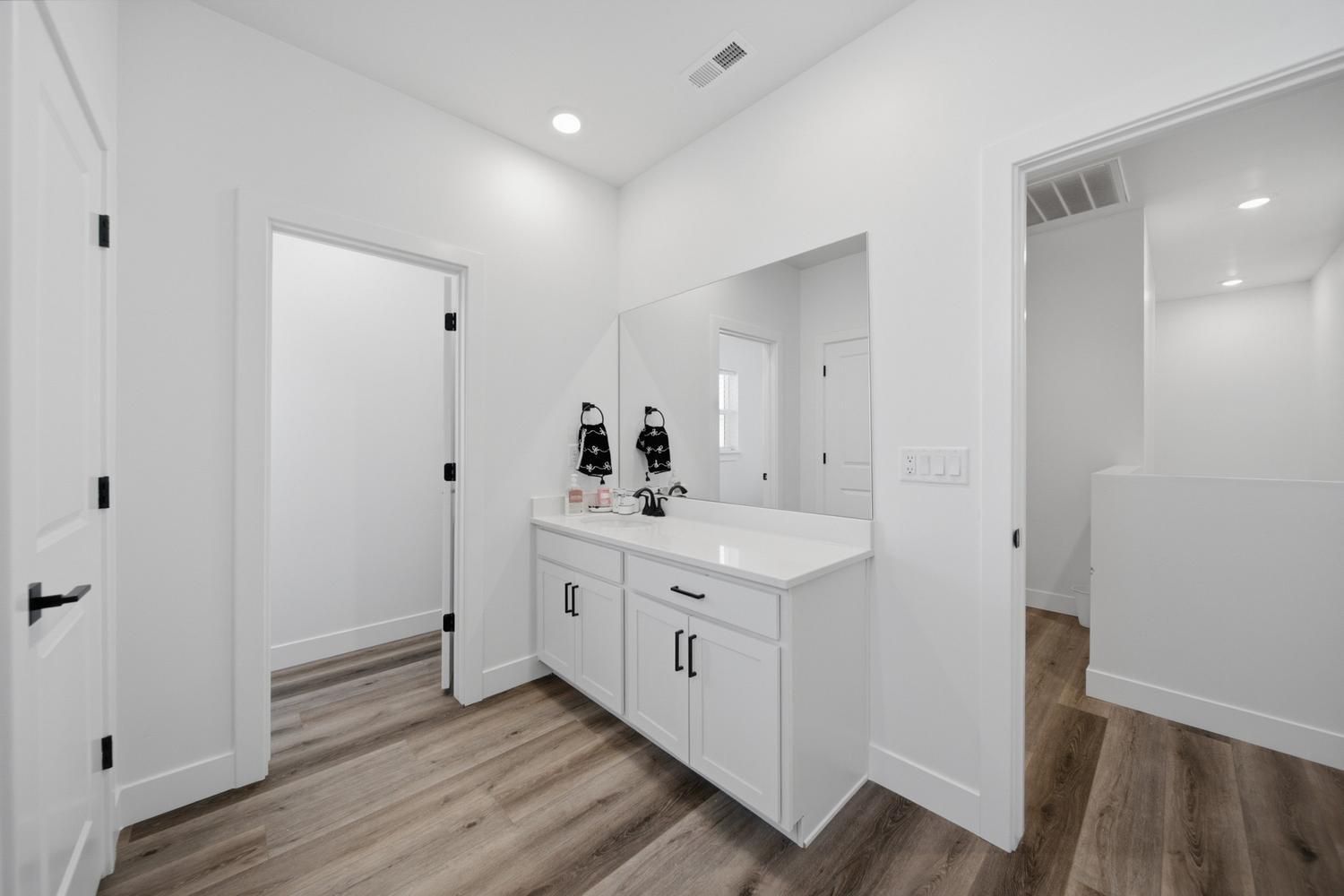 6144 Red Sand Lane St. George, UT 84790 - Photo 9 of 19 At the end of a quiet hallway, this powder-style vanity area offers a quartz counter, ample cabinet storage, and a large mirror framed by soft sconce lighting overhead. The adjoining doors provide privacy while keeping the space well connected to the surrounding living areas.