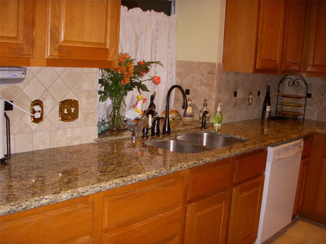 a kitchen with granite countertop a sink a stove and a wooden cabinets