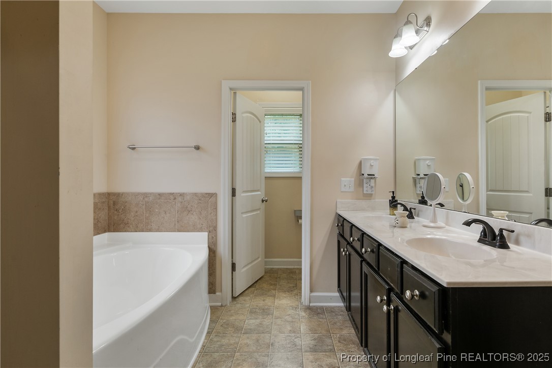 945 Pecan Grove Loop Hope Mills, NC 28348 - Photo 25 of 42 a bathroom with a tub a double vanity sink and a mirror