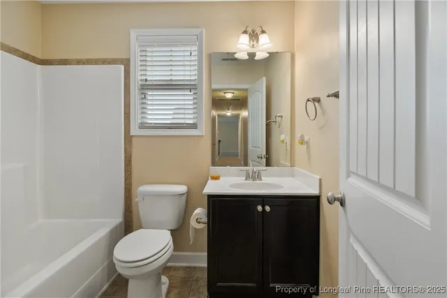 a bathroom with a granite countertop bathtub shower sink vanity and toilet